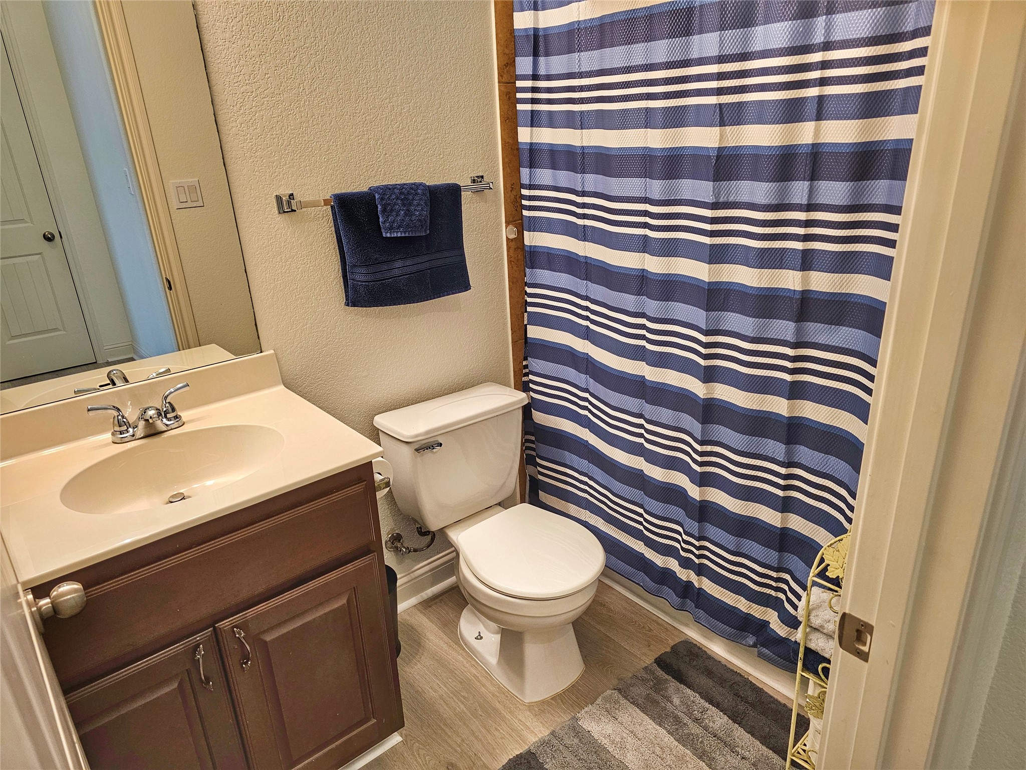 11508 Flushwing Drive Austin, TX 78754 - Photo 19 of 24 Bathroom with a textured wall, vanity, curtained shower, and light wood-type flooring