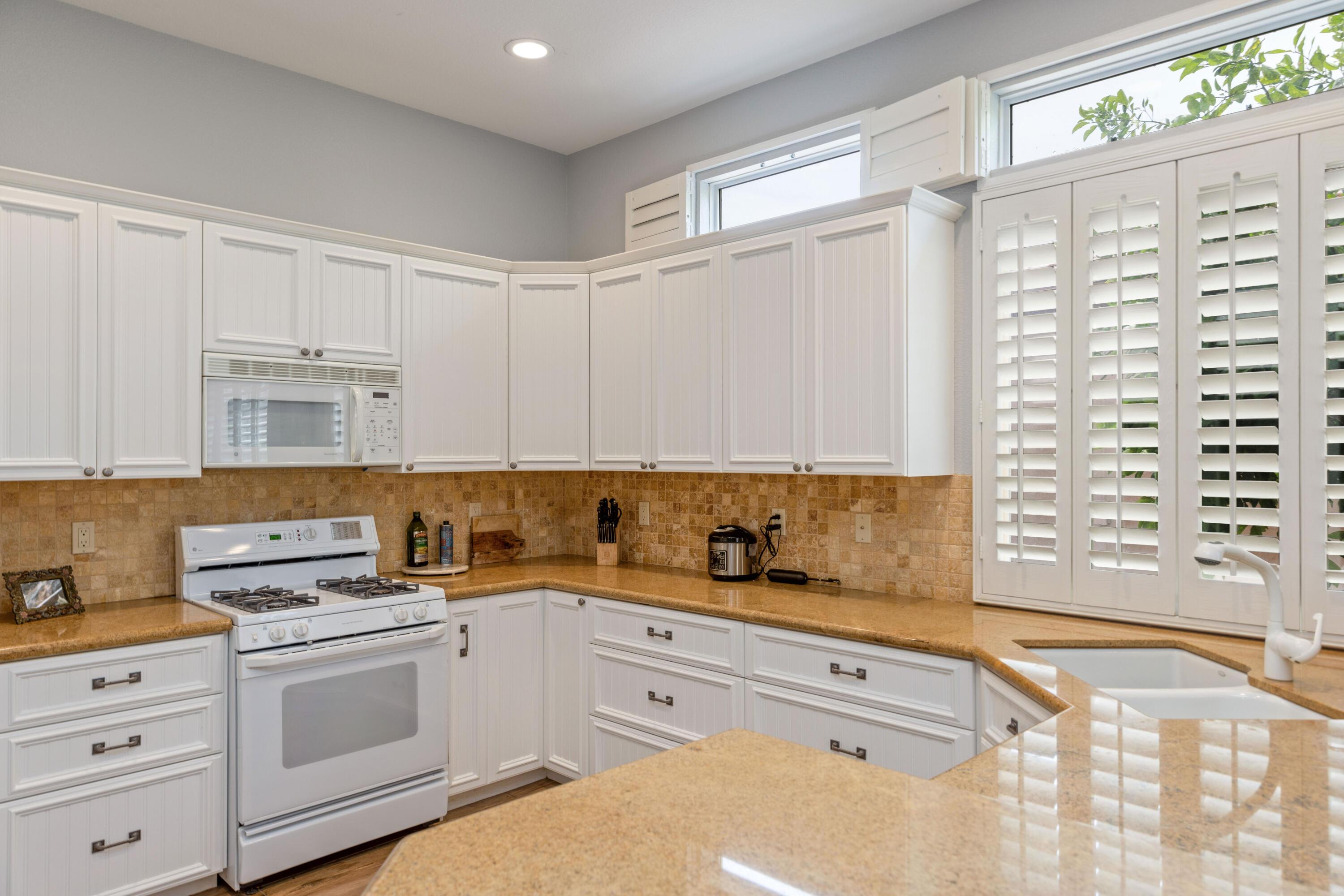 44357 Royal Lytham Drive Indio, CA 92201 - Photo 7 of 21 a kitchen with granite countertop white cabinets and white appliances