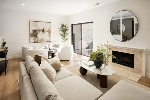 a living room with couches a fireplace and a potted plant