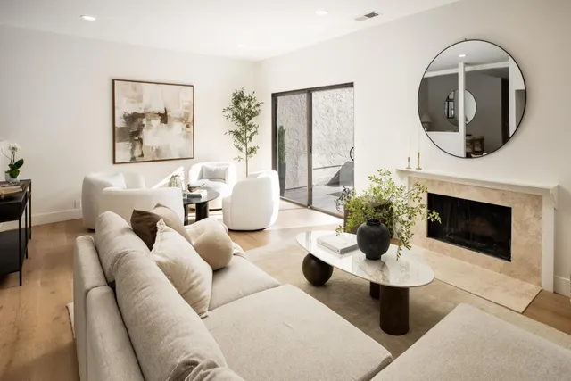 a living room with couches a fireplace and a potted plant