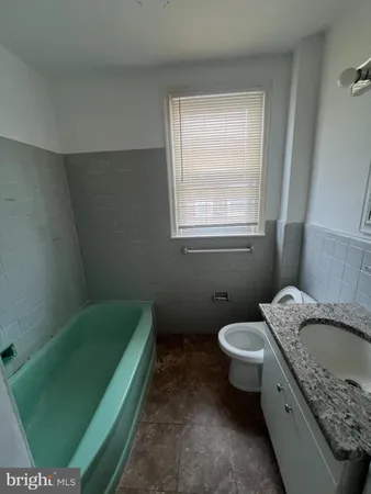 a bathroom with a granite countertop toilet sink and window