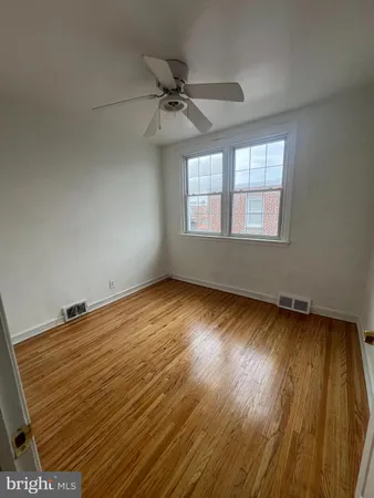 an empty room with wooden floor fan and windows