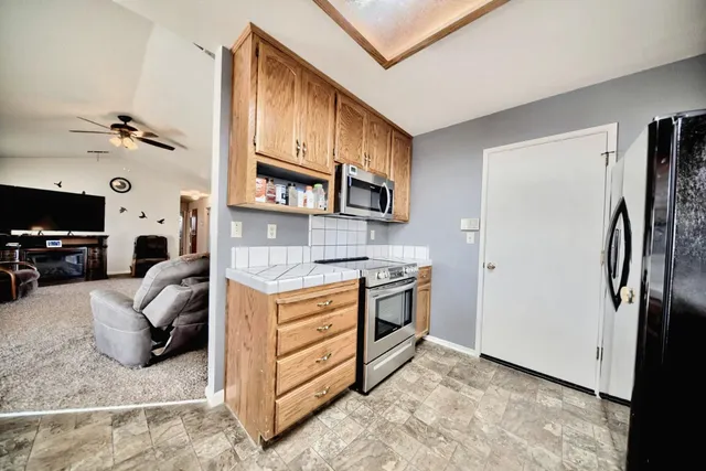 a kitchen with stainless steel appliances kitchen island granite countertop a stove a sink a dining table and chairs