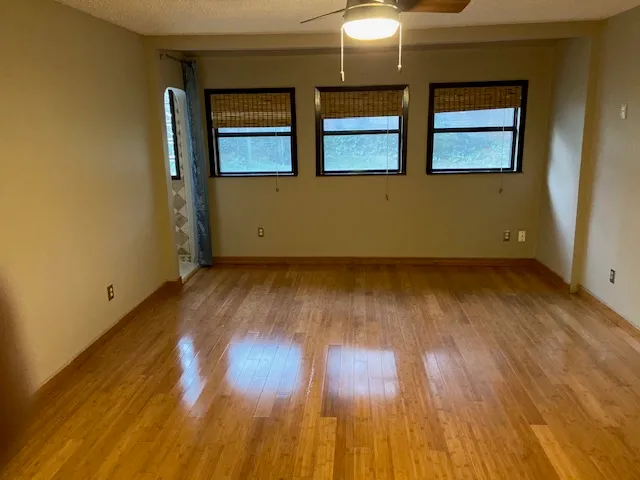 an empty room with wooden floor and windows