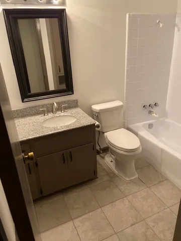a bathroom with a granite countertop sink toilet and mirror