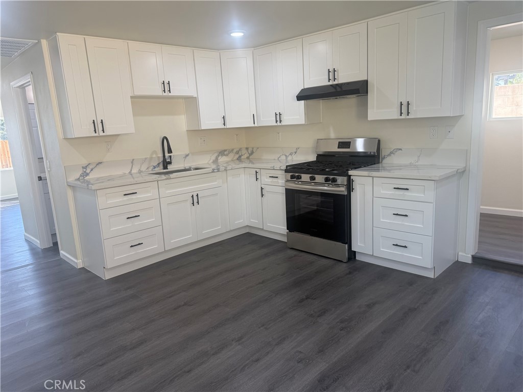 10337 Mull Avenue Riverside, CA 92505 - Photo 12 of 28 a kitchen with stainless steel appliances white cabinets and wooden floors