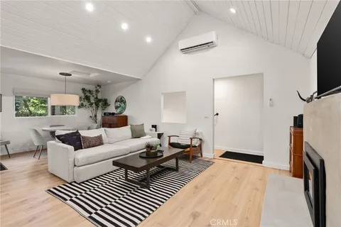 a living room with furniture a flat screen tv and a refrigerator