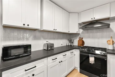 a kitchen with stainless steel appliances granite countertop white cabinets and a stove a oven with white countertops