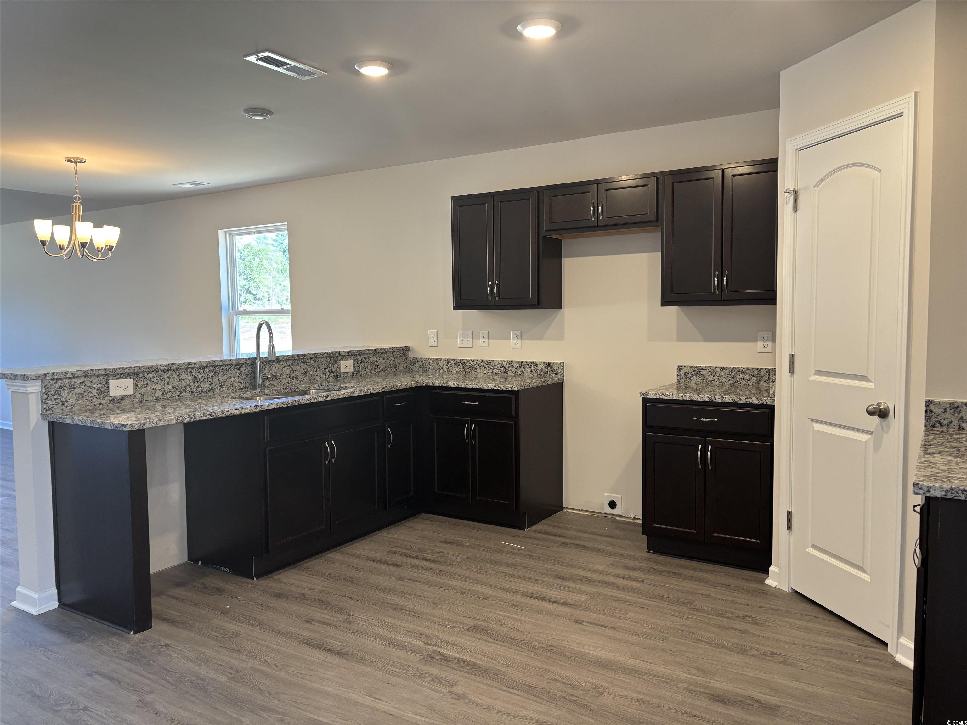 5729 Highway 41 Marion, SC 29571 - Photo 2 of 8 Kitchen with light stone countertops, dark wood-type flooring, a peninsula, and dark cabinetry