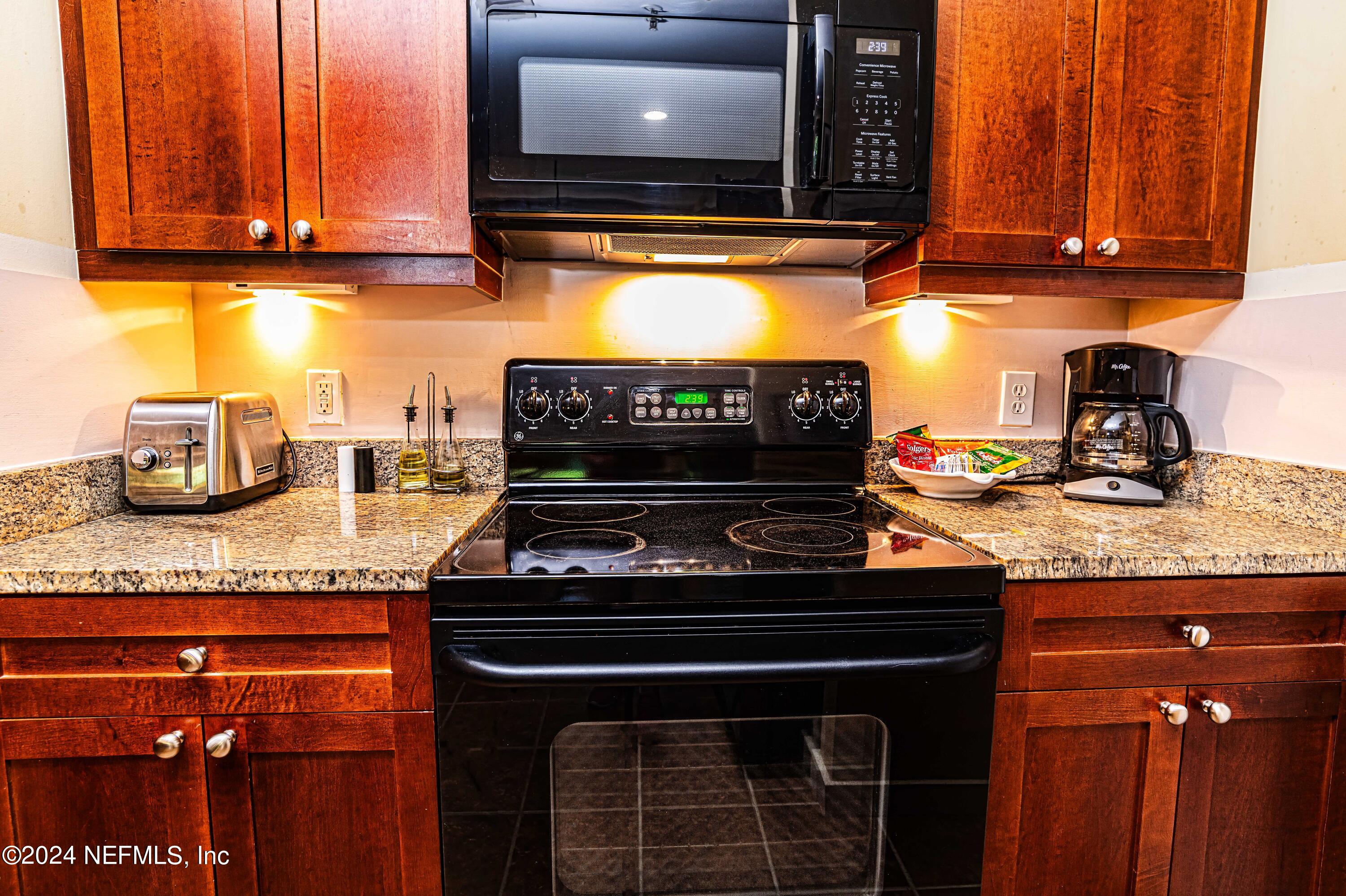 955 Registry Boulevard, Unit 229 St. Augustine, FL 32092 - Photo 18 of 36 a kitchen with granite countertop a stove and cabinets