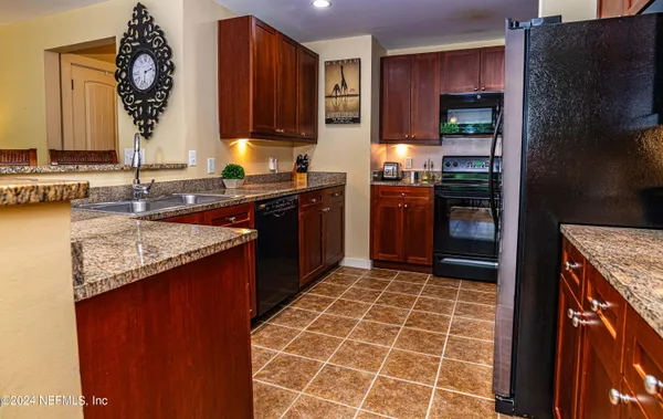 a kitchen with granite countertop a stove a sink and a refrigerator