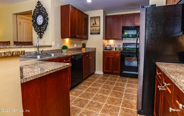 a kitchen with granite countertop a stove a sink and a refrigerator