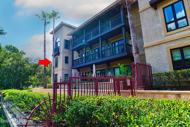 a view of a brick house with large windows and flower plants