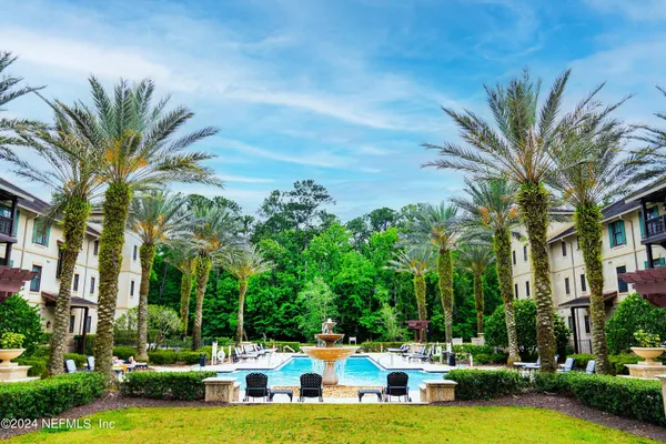 a view of a swimming pool with lawn chairs and a big yard