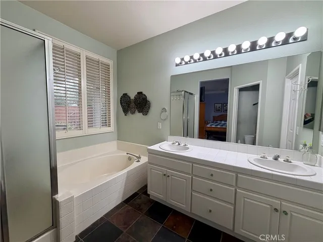 a bathroom with a tub a double vanity sink and mirror