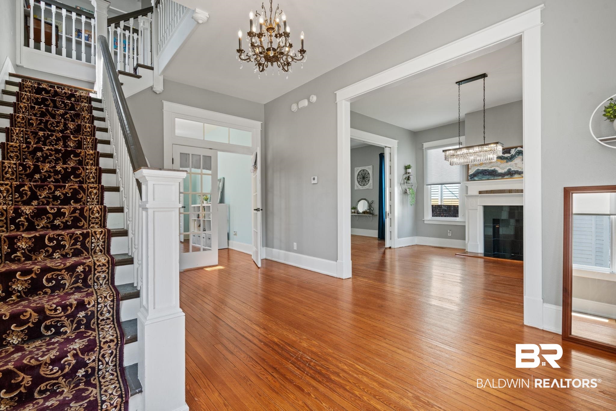 10 South Monterey Street Mobile, AL 36604 - Photo 19 of 45 Foyer entrance featuring a chandelier, light wood-style floors, a glass covered fireplace, and stairway