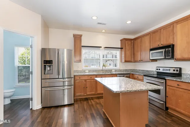 a kitchen with granite countertop a refrigerator stove and sink