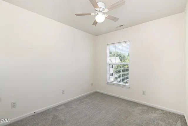 an empty room with a window and ceiling fan