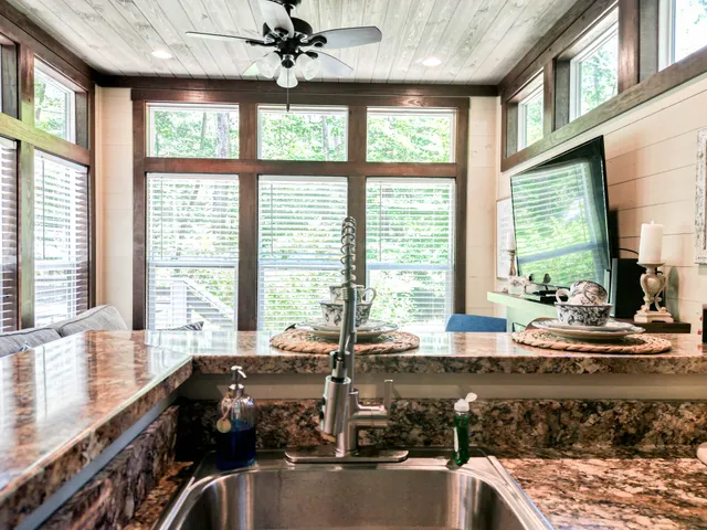 a view of a kitchen with kitchen island a large window cabinets a sink and stainless steel appliances