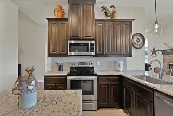 a kitchen with stainless steel appliances granite countertop a stove a sink and a microwave