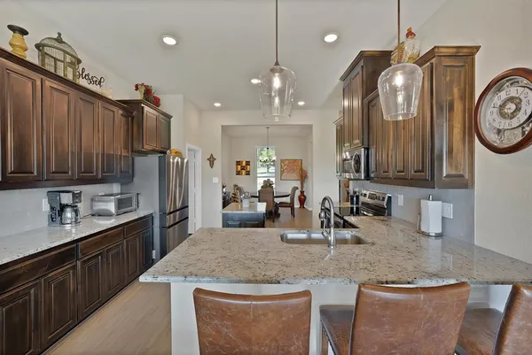a kitchen with stainless steel appliances granite countertop a sink a stove and a wooden cabinets