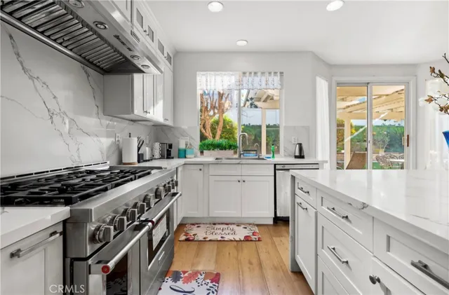 a kitchen with white cabinets a stove and a window