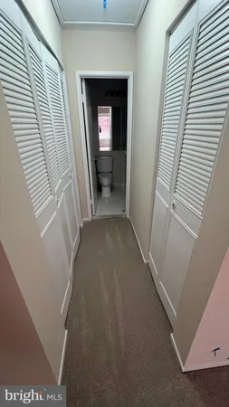 a view of a hallway with wooden floor and a living room