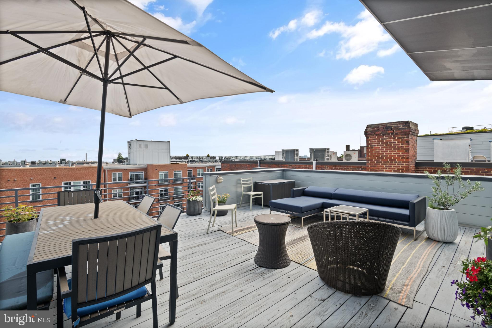 1436 Chapin Street Northwest, Unit F Washington, DC 20009 - Photo 36 of 41 a view of a roof deck with table and chairs under an umbrella with wooden floor