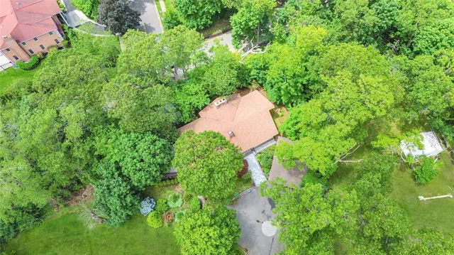 an aerial view of residential house with outdoor space and trees all around