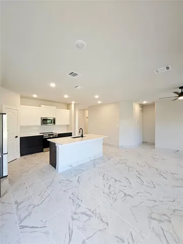 a view of kitchen with kitchen island a sink a counter top stainless steel appliances and cabinets