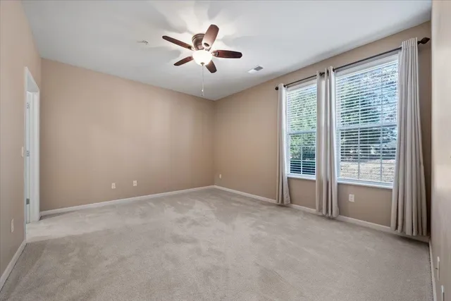 an empty room with windows and ceiling fan
