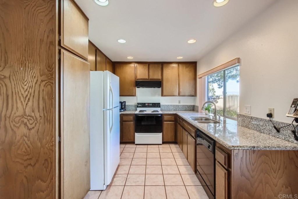 404 Compass Road Oceanside, CA 92054 - Photo 7 of 26 a kitchen with stainless steel appliances granite countertop a refrigerator a sink dishwasher a stove with wooden cabinets and floor