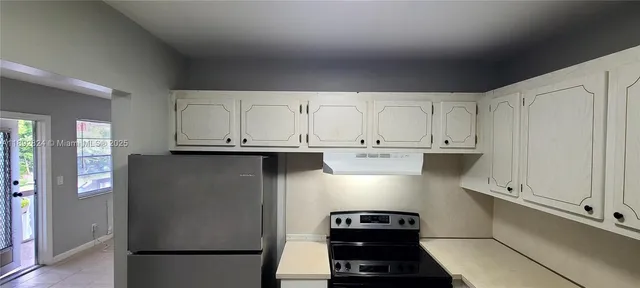 a kitchen with kitchen island white cabinets and refrigerator