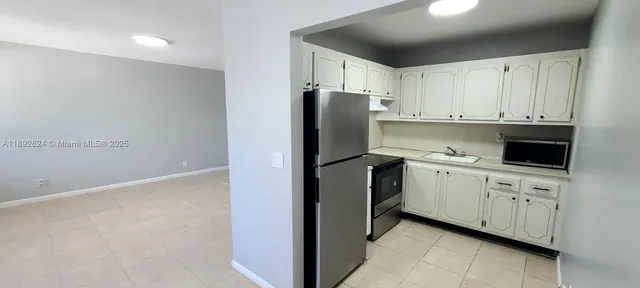 a kitchen with white cabinets and refrigerator