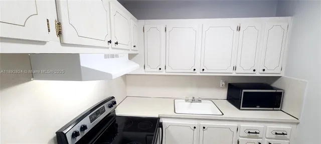 a kitchen with white cabinets and sink