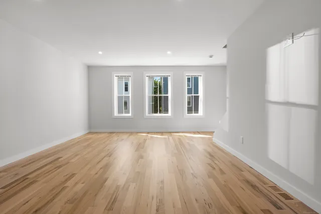 a view of an empty room with a window and wooden floor