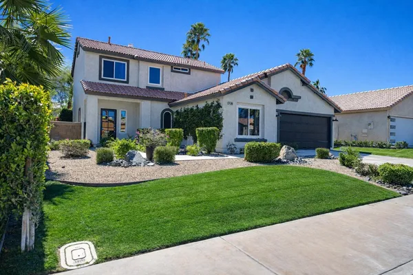 a front view of a house with a yard and potted plants