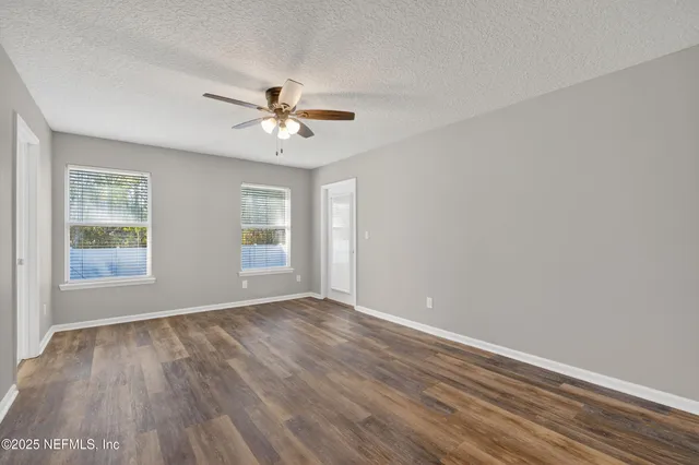 a view of empty room with wooden floor and fan