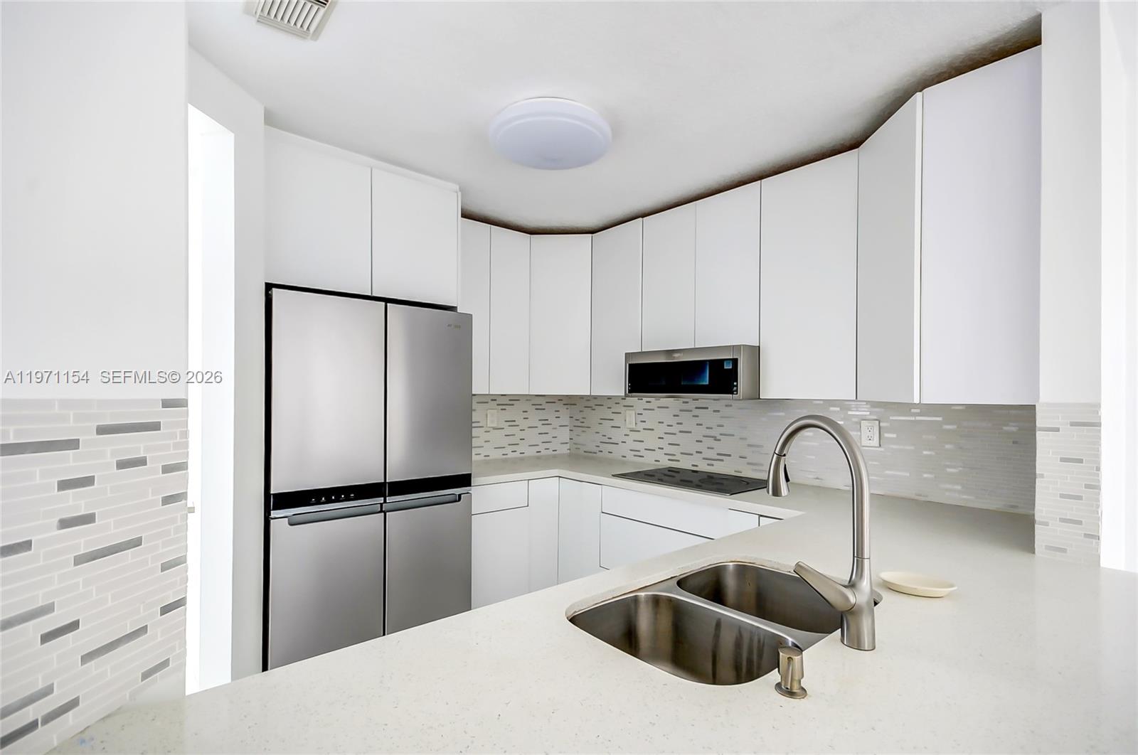 12909 Southwest 61st Terrace Miami, FL 33183 - Photo 11 of 36 a kitchen with a sink a refrigerator and cabinets