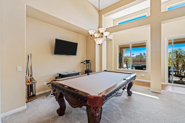 a room with furniture pool table flat screen tv and windows