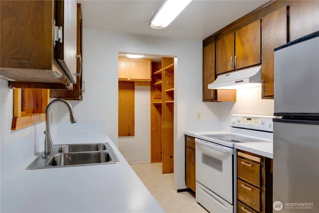 a kitchen with stainless steel appliances a stove a sink a refrigerator a counter space and cabinets