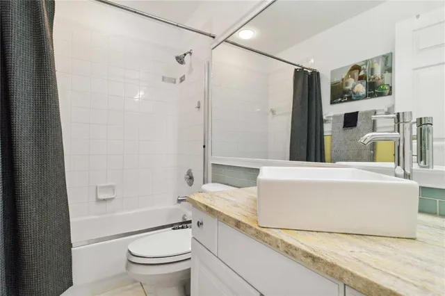 a bathroom with a granite countertop sink a toilet a mirror and shower