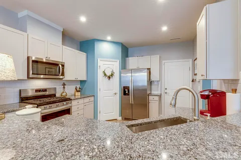 a kitchen with stainless steel appliances granite countertop a refrigerator a stove a sink and a microwave