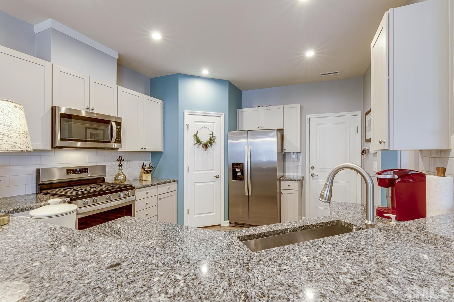 3155 Retama Run New Hill, NC 27562 - Photo 16 of 48 a kitchen with stainless steel appliances granite countertop a refrigerator a stove a sink and a microwave