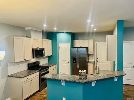 a kitchen with kitchen island granite countertop stainless steel appliances and refrigerator