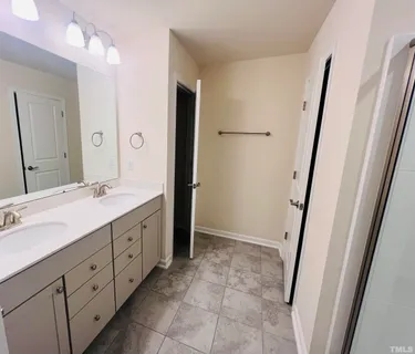 a spacious bathroom with a double vanity sink a mirror and a shower