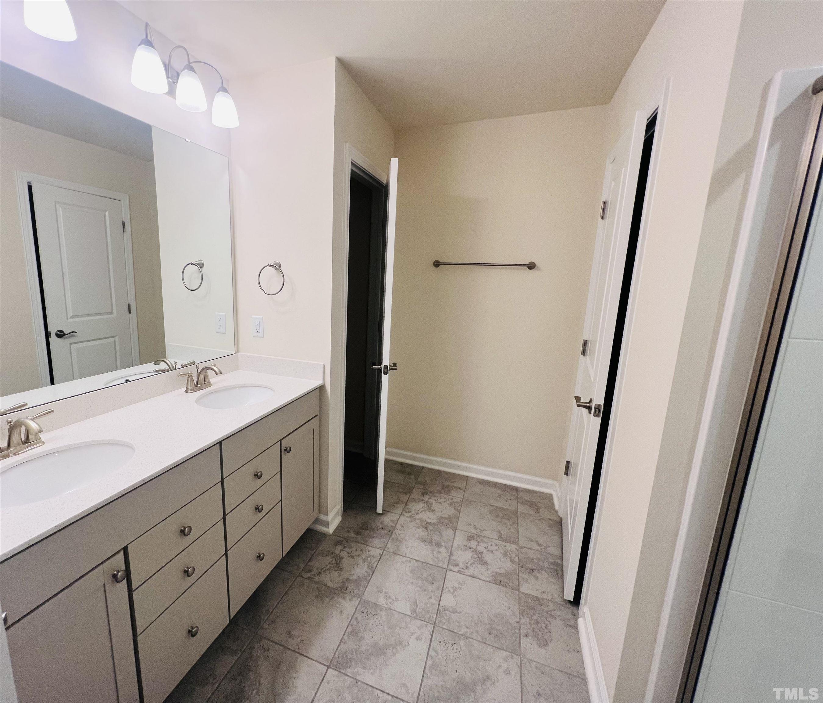 3155 Retama Run New Hill, NC 27562 - Photo 31 of 48 a spacious bathroom with a double vanity sink a mirror and a shower