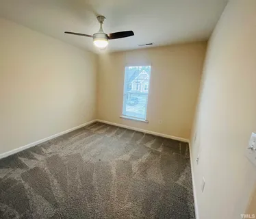 an empty room with a window and a fan