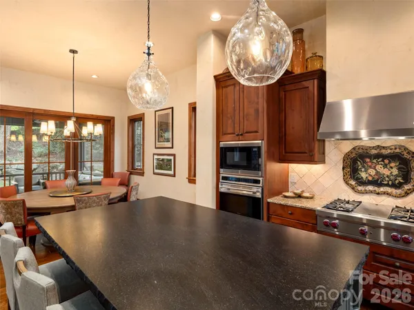 a kitchen with stainless steel appliances granite countertop a stove a sink and a dining table with wooden floor
