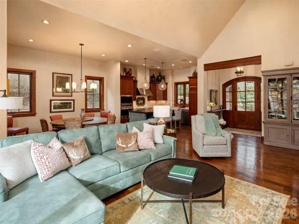 a living room with furniture kitchen view and a wooden floor